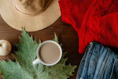 Sonbaharın düz lay ahşap arka plan üzerinde sıcak giysiler fincan kahve ve sonbahar yaprak düşer. Sonbahar sonbahar rahat kavramı