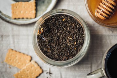 Tıbbi çay bitkileri varyasyon. Bardak, kaşık, bisquits, ballı çay yaprakları masa örtüsü arka plan üzerinde seçici odak kurutulmuş.