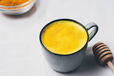 Altın süt Kupası, düz beyaz arka plan üzerinde zerdeçal tozu ile üstten görünüm yatıyordu. Detoks sağlıklı beslenme, enerji artırılması, gribi düzeltme, doğal soğuk içecek mücadele. Diyet, kilo kaybı kavramı, kış sıcak içecek