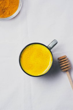 Altın süt Kupası, düz beyaz arka plan üzerinde zerdeçal tozu ile üstten görünüm yatıyordu. Detoks sağlıklı beslenme, enerji artırılması, gribi düzeltme, doğal soğuk içecek mücadele. Diyet, kilo kaybı kavramı, kış sıcak içecek