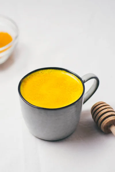 Golden milk with turmeric powder in cup over white background, flat lay top view. Detox healthy eating, energy boosting, flu remedy, natural cold fighting drink. dieting, weight loss concept, winter hot drink