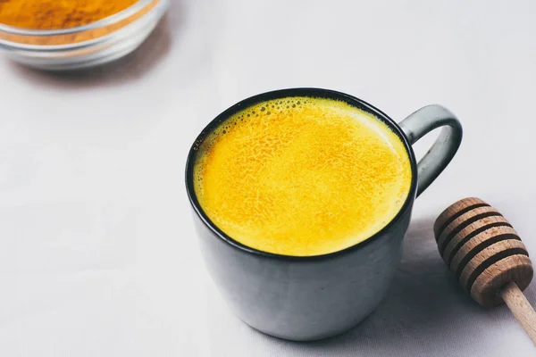 Altın süt Kupası, düz beyaz arka plan üzerinde zerdeçal tozu ile üstten görünüm yatıyordu. Detoks sağlıklı beslenme, enerji artırılması, gribi düzeltme, doğal soğuk içecek mücadele. Diyet, kilo kaybı kavramı, kış sıcak içecek
