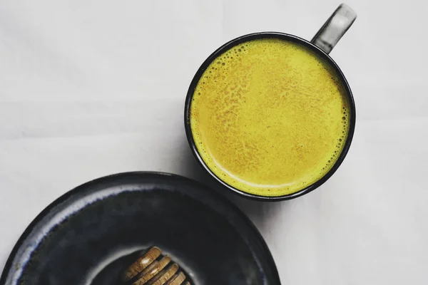 Altın süt Kupası, düz beyaz arka plan üzerinde zerdeçal tozu ile üstten görünüm yatıyordu. Detoks sağlıklı beslenme, enerji artırılması, gribi düzeltme, doğal soğuk içecek mücadele. Diyet, kilo kaybı kavramı, kış sıcak içecek