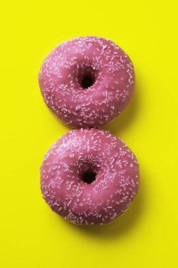 Yukarıdan sarı arka plan üzerinde iki sırlı donut ile görüntüleyin. 8 Mart kadın günü için arka plan. 8 Mart ve kadın gün kavramı.
