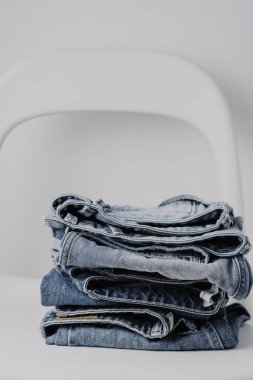 Beyaz arka plan, minimalist kavramı, minimalist tarzda beyaz sandalye üzerinde kot pantolon