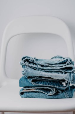 Beyaz arka plan, minimalist kavramı, minimalist tarzda beyaz sandalye üzerinde kot pantolon