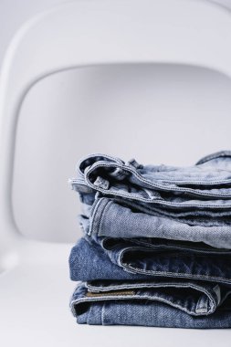 Beyaz arka plan, minimalist kavramı, minimalist tarzda beyaz sandalye üzerinde kot pantolon