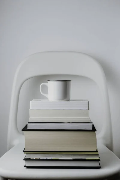 white mug with coffee or tea on books over white background. Minimalist style, education, science, research, hygge concept