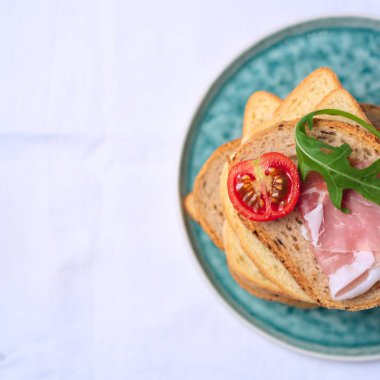 kare kırpma düz lezzetli taze ekmek parçaları ile ham domates ve roket salata plat üzerinde beyaz arka plan üzerinde göklere 