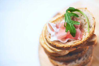 jambon ve roket salata ahşap tahta üzerinde taze lezzetli ekmek. Atıştırma, brunch veya kahvaltı lezzetli İtalyan snack 
