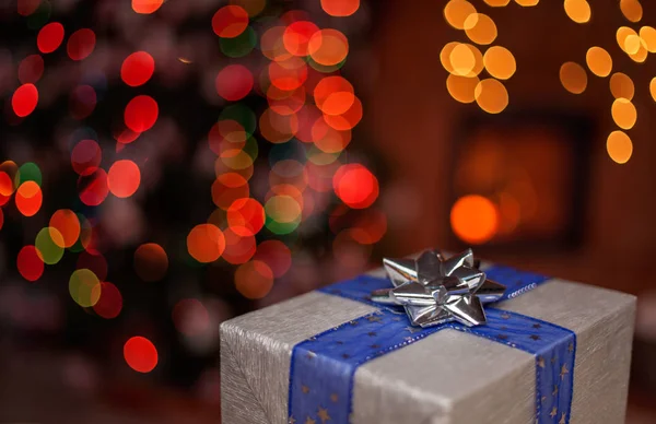 Een Kerstcadeau Met Decoratieve Lint Een Donkere Kamer Met Kerstboom — Stockfoto