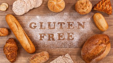 Gluten free bakery products around words written in special flour on the table - the allergen free alternative, top view clipart