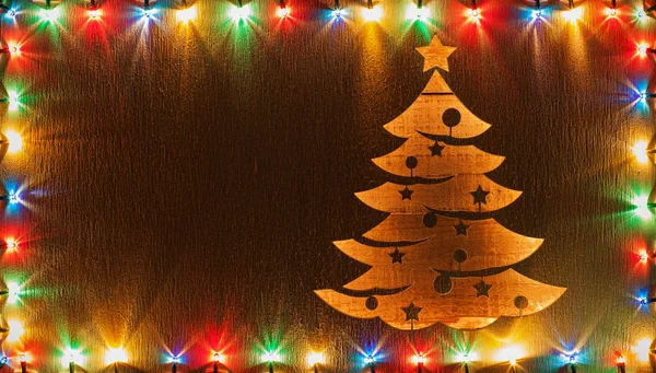 圣诞树形状削减在木板上 从下面点燃五颜六色的圣诞灯框架 复制空间 节日问候设计 — 图库照片
