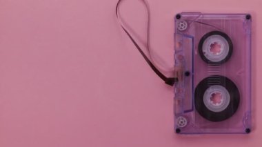 Retro müzik kompakt kaset withrawing asılı ve sonra oynama, pembe arka plan - kopya alanı açığa ile durmak devinim bandı ile