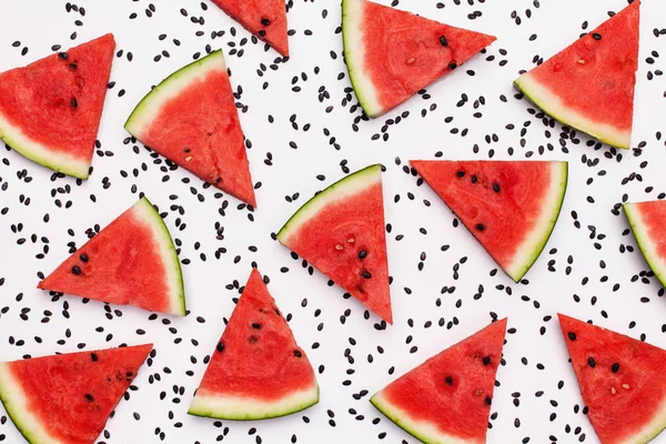 Watermelon slices among black melon seeds on white surface — Stock Photo, Image