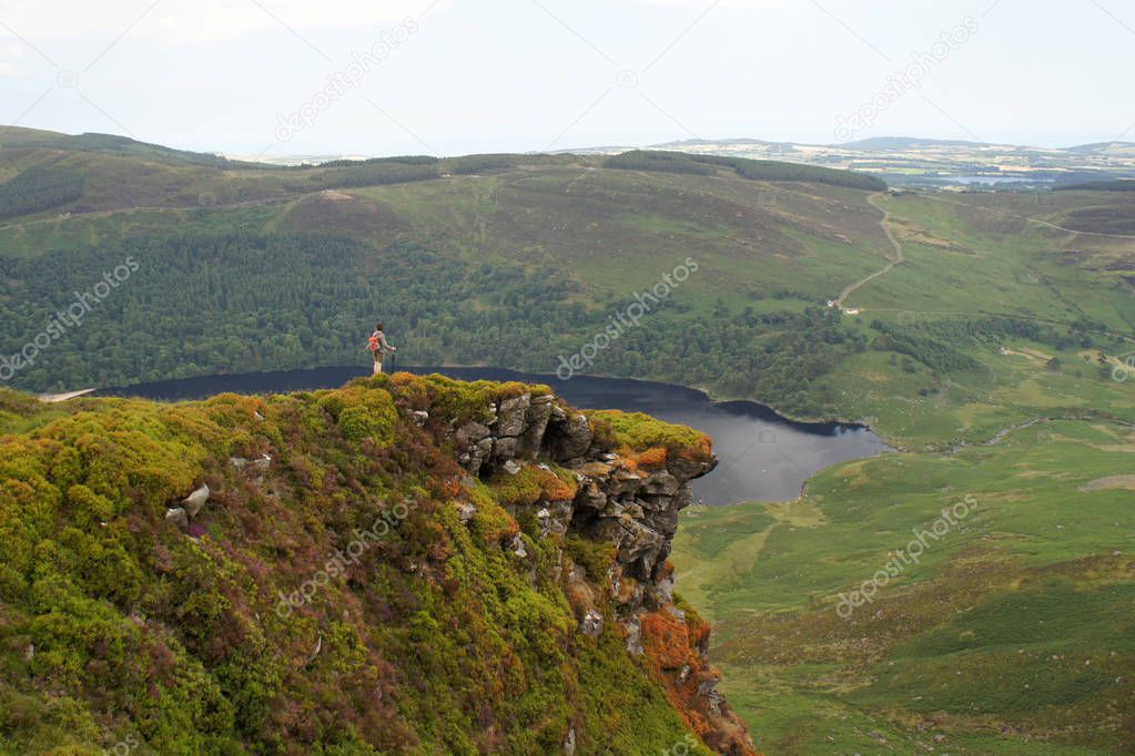 A tourist on a rock above a mountain valley.Ireland.