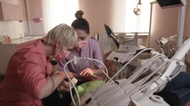 Diş hekimi inceler ve diş iyileştiriyor.