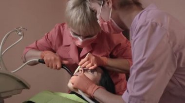 Diş hekimi inceler ve diş iyileştiriyor.