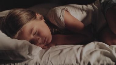 Baba küçük kızı yatağa koyar..