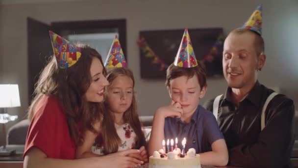 Menino faz um desejo e sopra velas em um bolo de aniversário — Vídeo de Stock