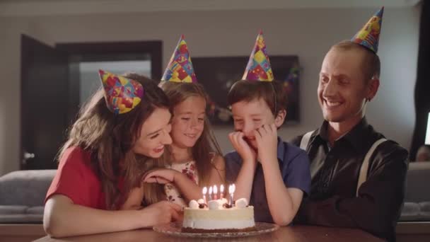 Menino faz um desejo e sopra velas em um bolo de aniversário — Vídeo de Stock