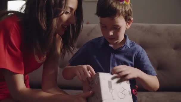 Junge mit Mutter öffnet ein Geburtstagsgeschenk — Stockvideo