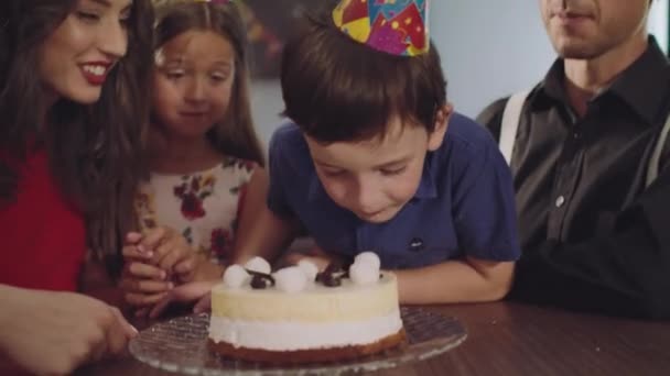 O menino morde um bolo de aniversário — Vídeo de Stock