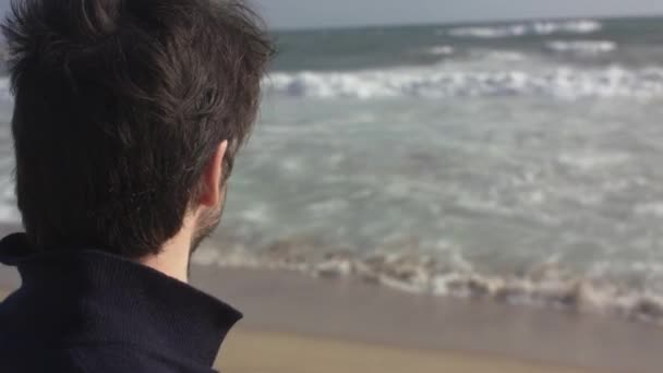 Задуманный человек, гуляющий по океанскому пляжу — стоковое видео