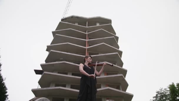 Krásná mladá žena hrající na housle u budovy. — Stock video