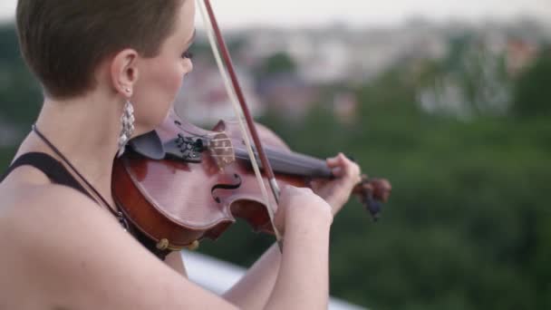 Красивая молодая женщина играет на скрипке на крыше . — стоковое видео