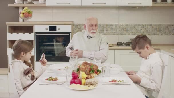 Nagypapa kommunikál unokái az asztalnál egy családi vacsora előtt — Stock videók
