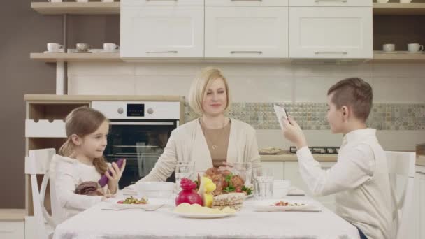 Mãe se comunica com seus filhos na mesa durante um jantar de família — Vídeo de Stock