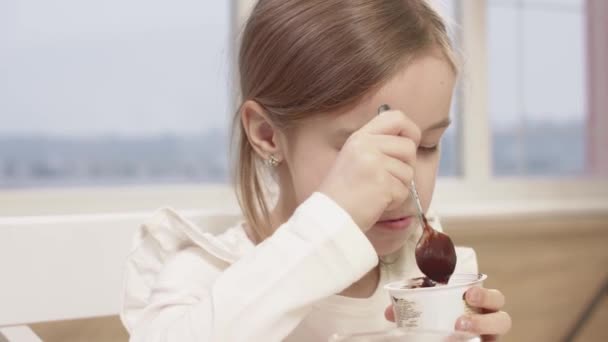 Meisje eet een heerlijke chocolademousse tijdens een familiediner — Stockvideo