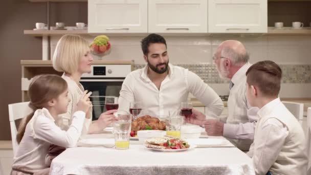 Familjen sitter runt ett bord, äta, kommunicera och ha roligt under familjemiddag. — Stockvideo