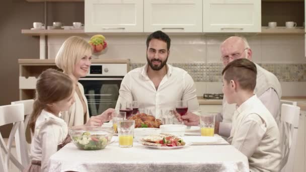 Rodina sedí kolem stolu, jíst, komunikace a baví při rodinné večeři. — Stock video