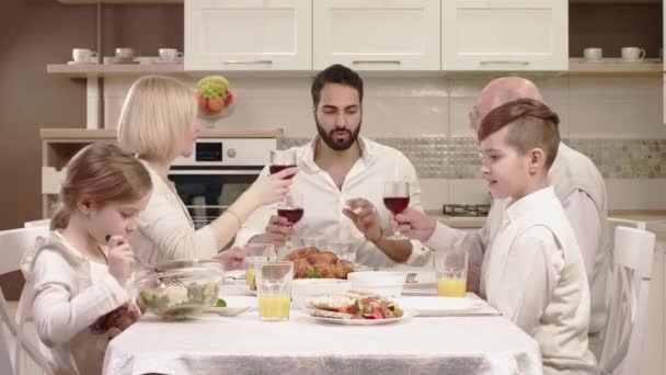 Rodina sedí kolem stolu, jíst, komunikace a baví při rodinné večeři. — Stock video