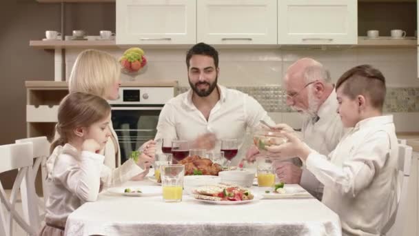 Familia sentada alrededor de una mesa, comiendo, comunicándose y divirtiéndose durante la cena familiar . — Vídeo de stock