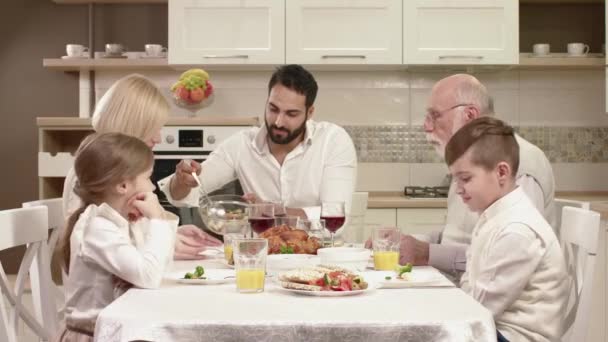 Família sentada em torno de uma mesa, comendo, comunicando e se divertindo durante o jantar em família . — Vídeo de Stock