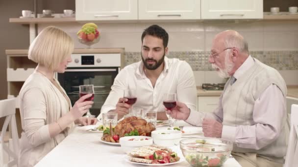 Familie sitzt am Tisch, isst, kommuniziert und amüsiert sich beim Familienessen. — Stockvideo
