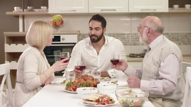 Семья, сидящая за столом, кушающая, общающаяся и развлекающаяся во время семейного ужина . — стоковое видео