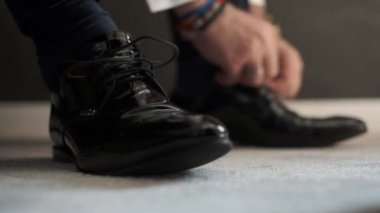 Damat dantel ayakkabılarla bağlı. Adam ayakkabı giymiyor.