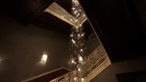 Lampadario di vetro di grandi dimensioni costoso in un ristorante o sala da concerto. Lampadario Illuminazione In Hall, Bokeh, Bagliore, Bagliore, Defocus . — Video Stock