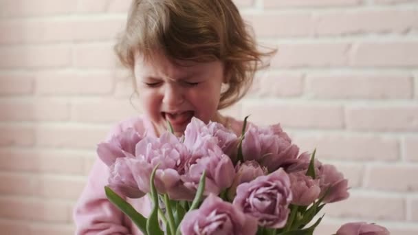 Retrato de um miúdo chorão com um ramo de flores nas mãos. Close-up . — Vídeo de Stock