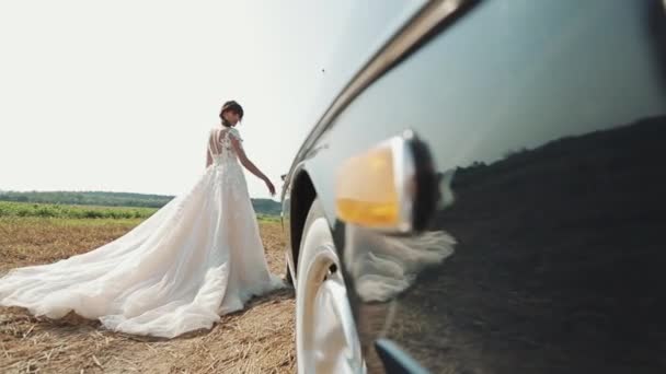 Jovem bela mulher no vestido de casamento posando perto de carro vintage . — Vídeo de Stock