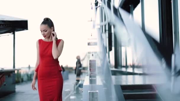 Schöne Mädchen in rotem formalen Kleid posiert auf der Straße an einem sonnigen Tag. — Stockvideo