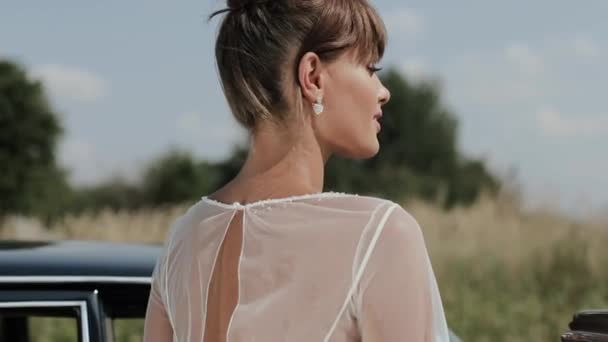 ヴィンテージカーの近くでポーズウェディングドレスの若い美しい女性. — ストック動画