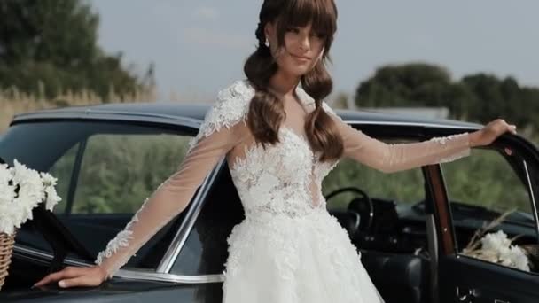 Joven hermosa mujer en vestido de novia posando cerca de coche Vintage . — Vídeo de stock