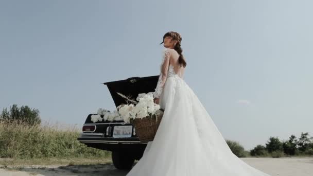 Jovem bela mulher no vestido de casamento posando perto de carro vintage . — Vídeo de Stock