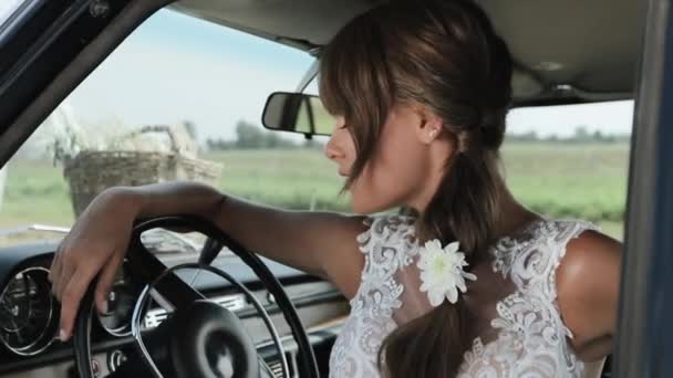 Junge schöne Frau im Hochzeitskleid posiert in Oldtimer. — Stockvideo