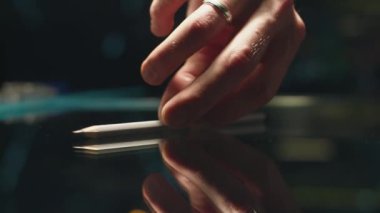 Kişi elinde bir kalem alır. Kişi masaya bir kalem koyar. Close.